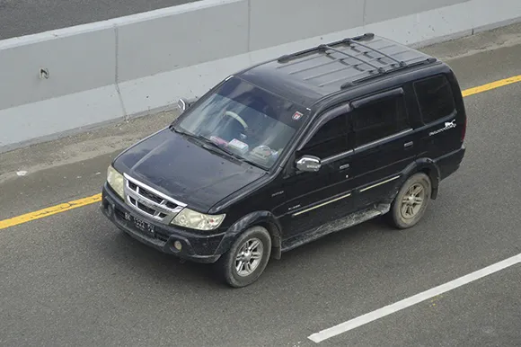 A black Isuzu Panther is being driven on the road.
