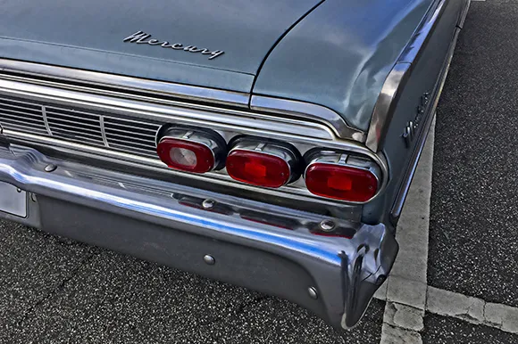 The read headlight of a classic blue Mercury car.