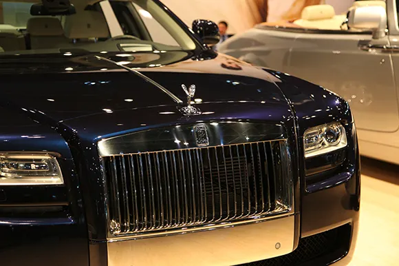 The hood of a dark blue Rolls Royce car at the New York International Auto Show.