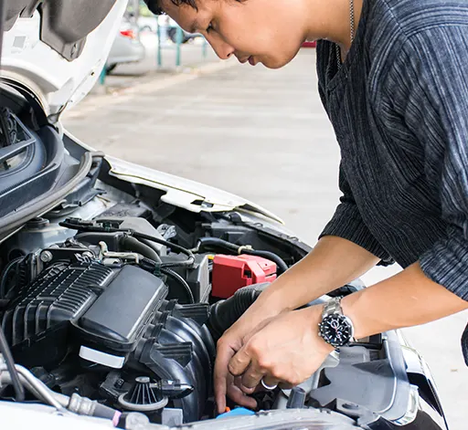 A man under the hood of a car checking his car engine
