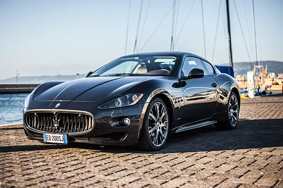 A black Maserati GranTurismo by the pier