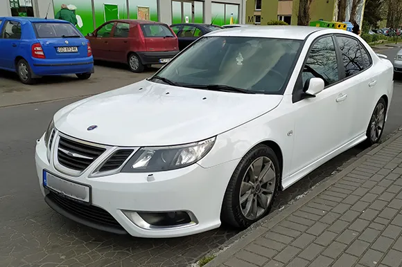 A white Saab Aero parked along the side of the road.