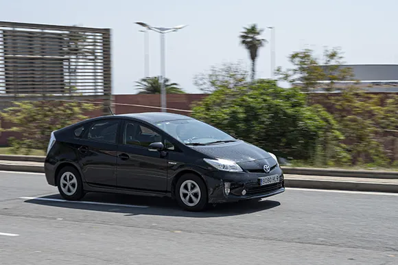A black Toyota Prius is being driven on the road.