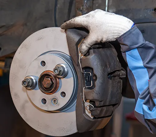 An auto mechanic replacing a worn brake pad