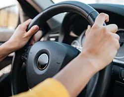 A driver firmly grasping a car's steering while