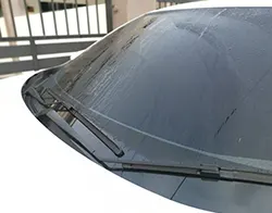 A car's front windshield covered in morning mist