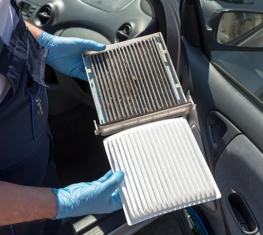A mechanic replacing a car's dirty cabin air filter