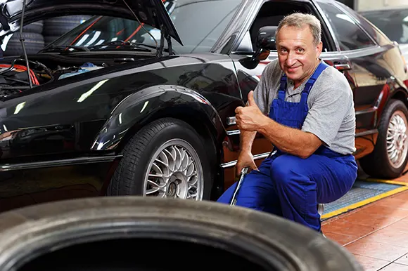 A car technician giving a thumbs up and who's about to work on a car