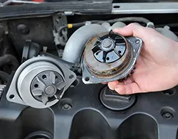 A mechanic removing and replacing a car's worn water pump