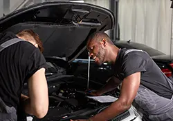 Two mechanics examining a car to prepare for maintenance service