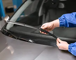 An auto technician removing a windshield wiper blade