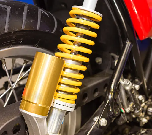 A shiny yellow shock absorber for a motorcycle.