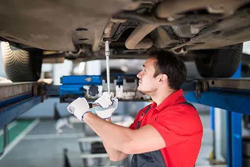 A professional auto mechanic working under a suspended car